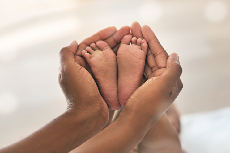 parent cupping the feet of a baby